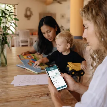 Working parent using a childcare app beside a young child