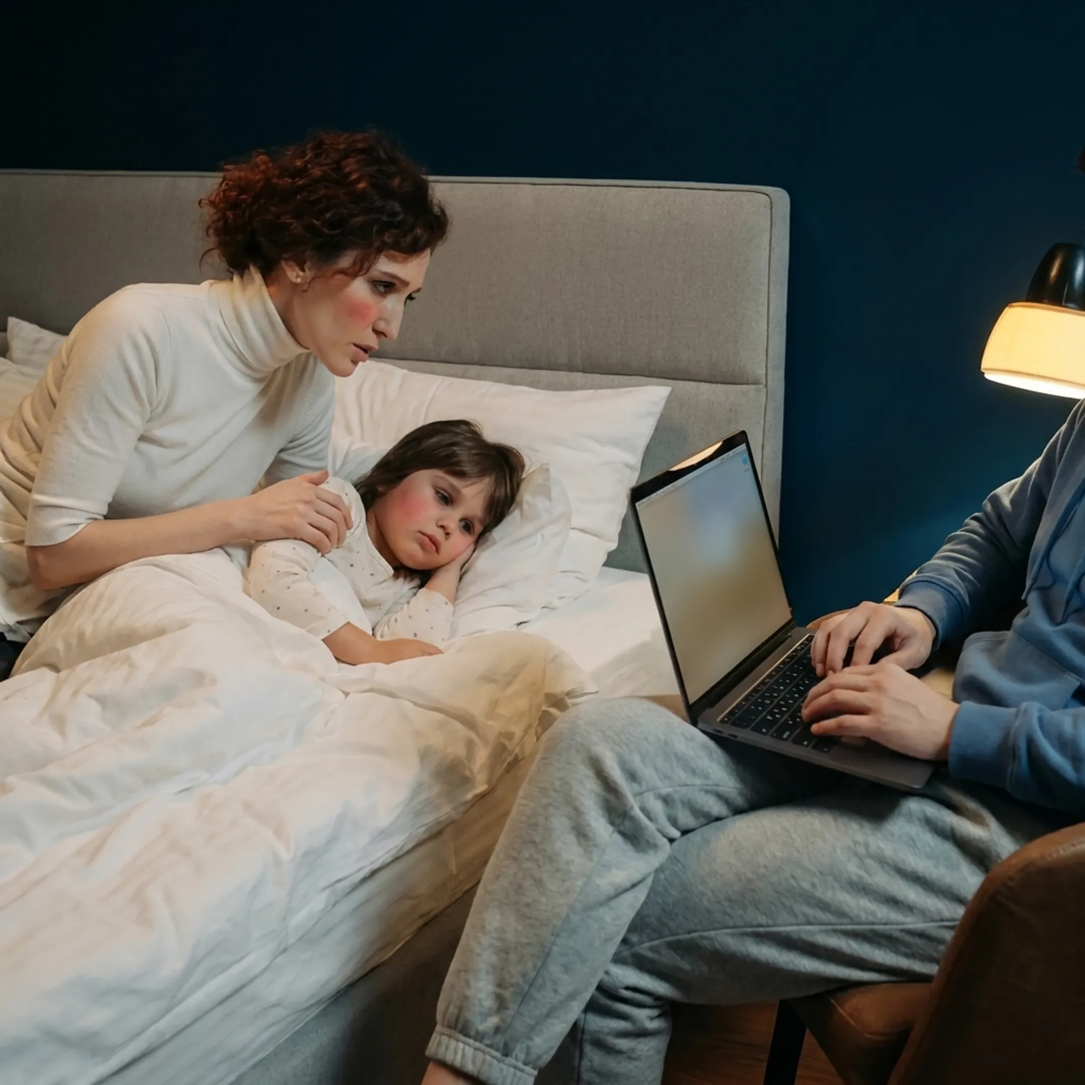 Caregiver tending to a sick child resting comfortably at home