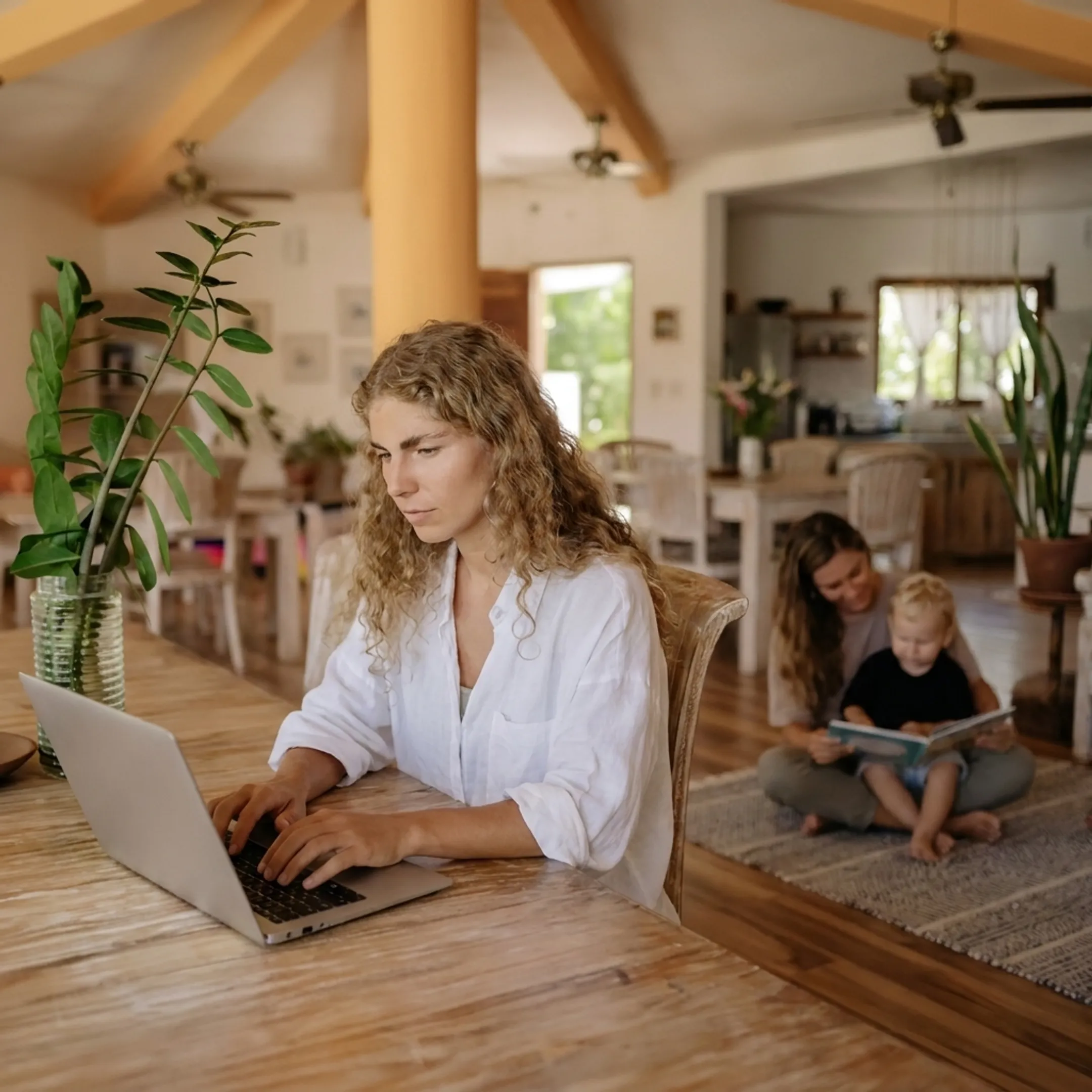 Working parent smiling while caring caregiver plays with child nearby