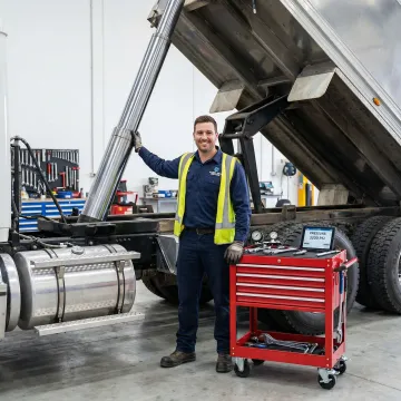 Hydraulic tipper system on dump truck being serviced by technician