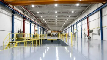 Industrial warehouse interior showing epoxy flooring LED high-bay lighting and safety guardrails