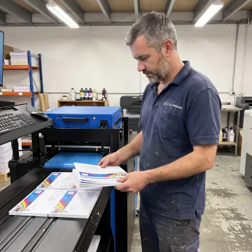 Operator inspecting full-color envelopes from an inkjet printer