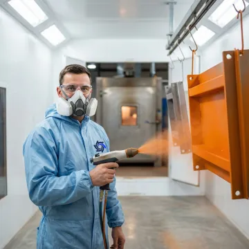 Industrial powder coating technician applying durable finish to metal components in a professional facility near Metro Detroit