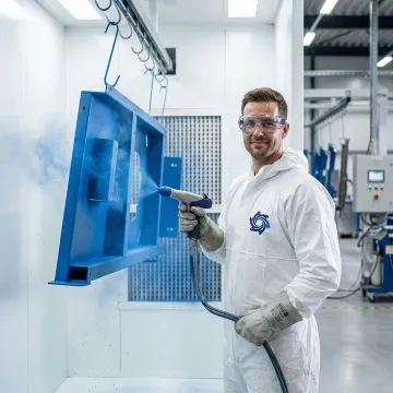 Professional powder coating technician applying uniform finish to metal components in an industrial facility