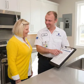Electrician walking a homeowner through electrical inspection findings on a clipboard