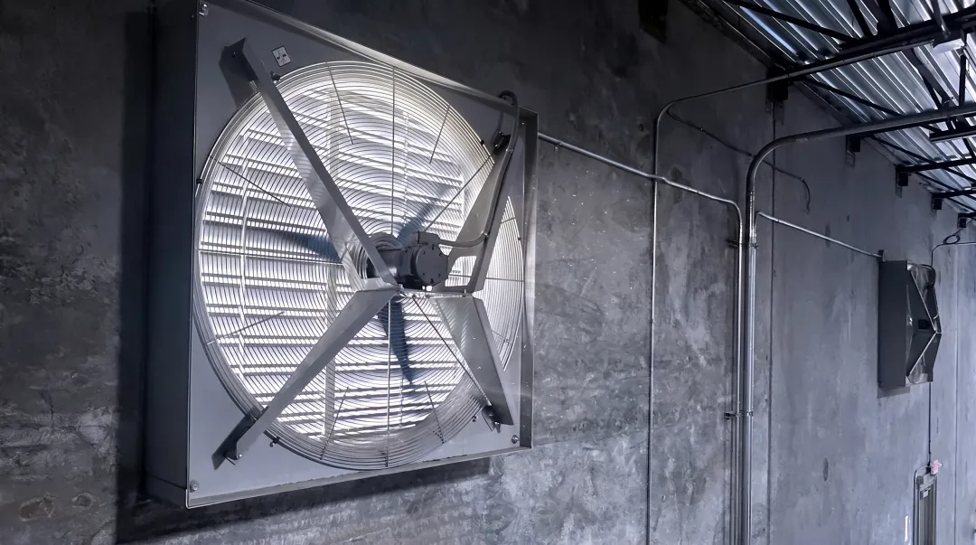 Industrial axial fan installed in warehouse showing propeller blade design and airflow direction