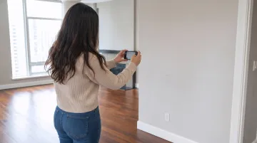 Renter photographing apartment walls and floors for move-out documentation