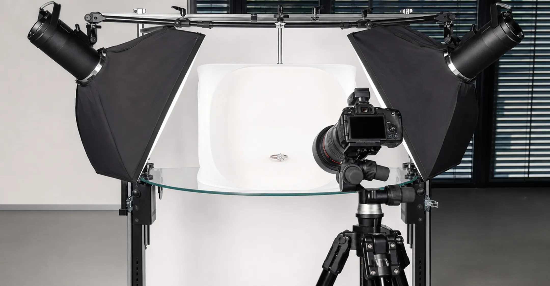 Macro camera setup on tripod photographing jewelry ring on white surface