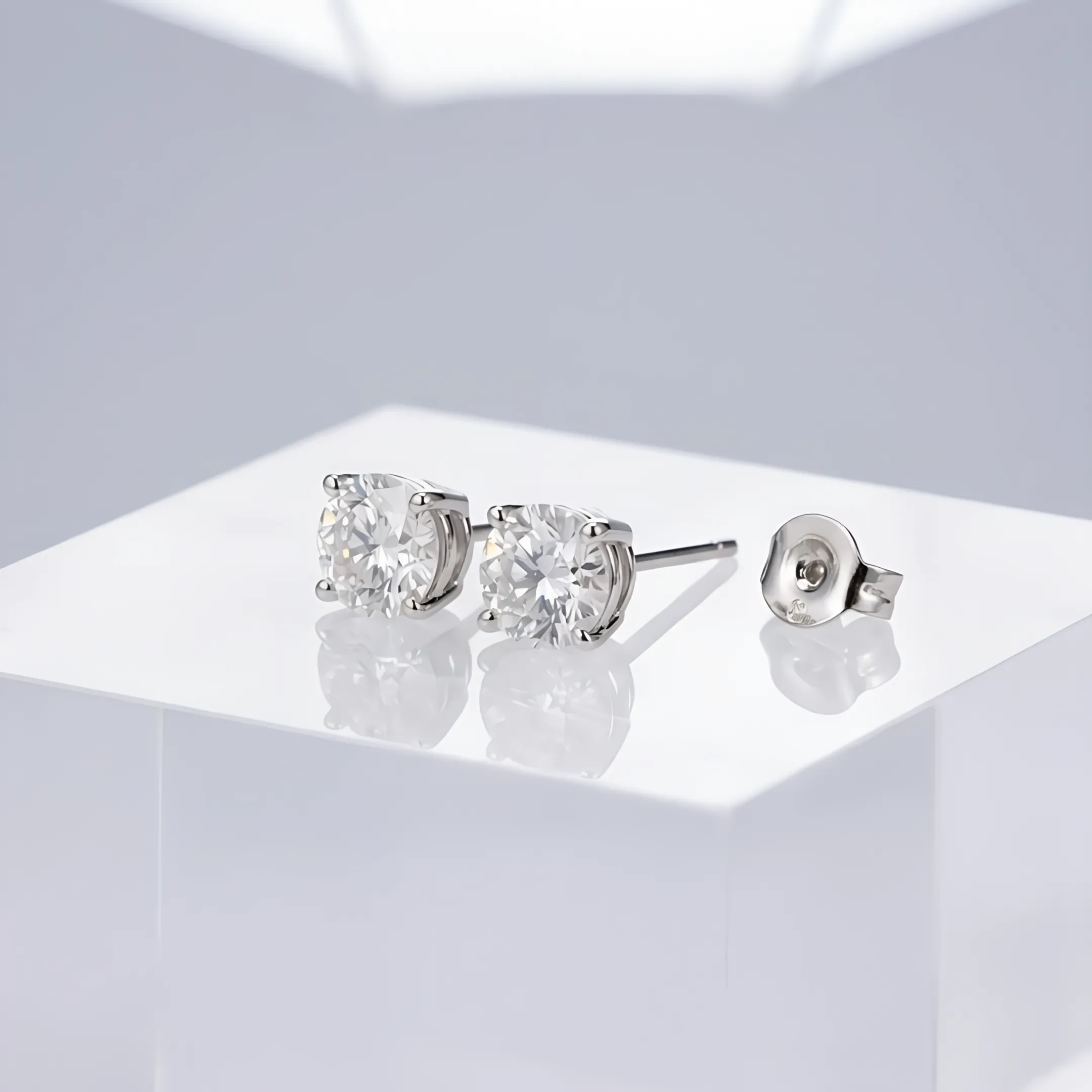 Studio jewelry photograph of diamond earrings displayed on clean acrylic background.
