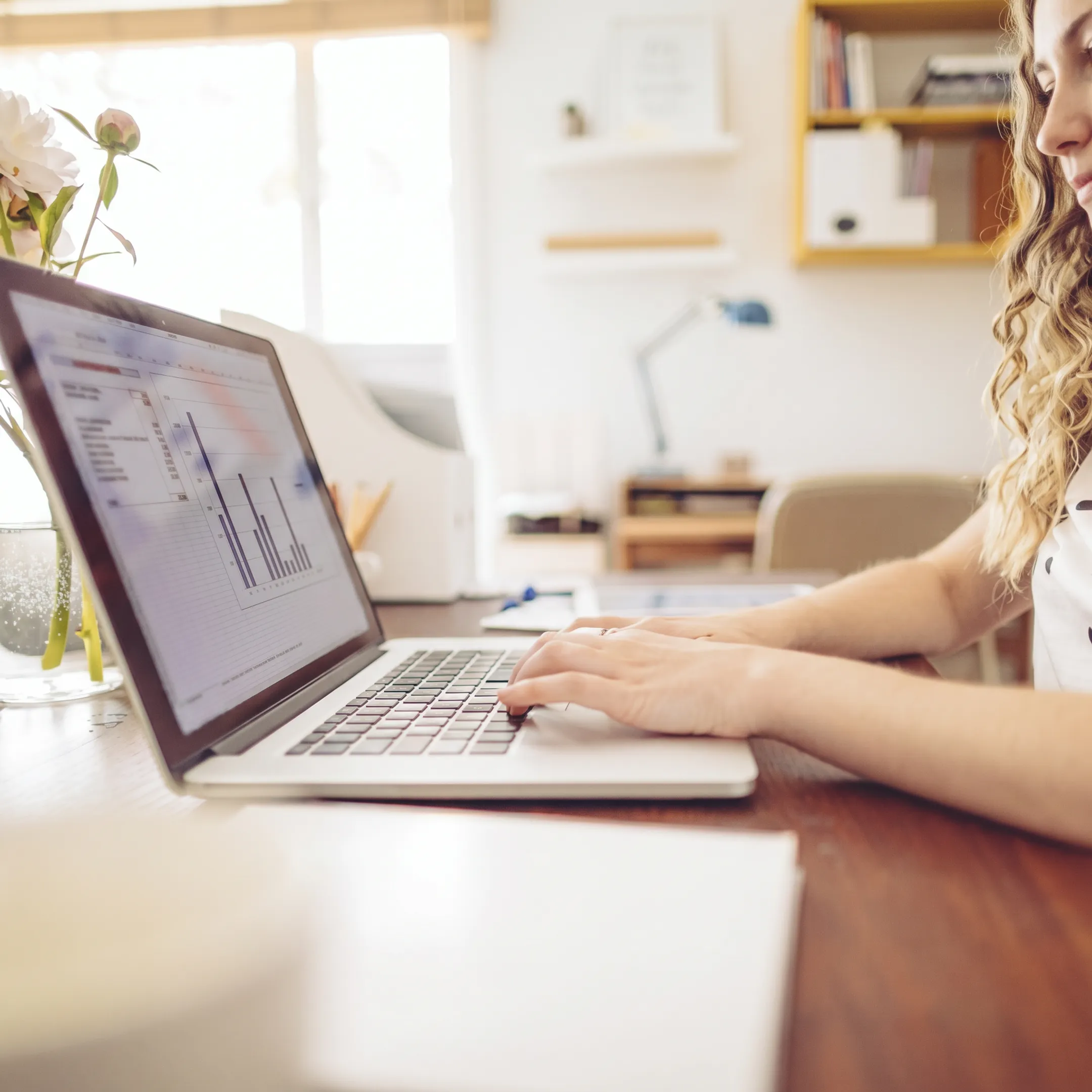 Professional reviewing organized bookkeeping reports on a laptop