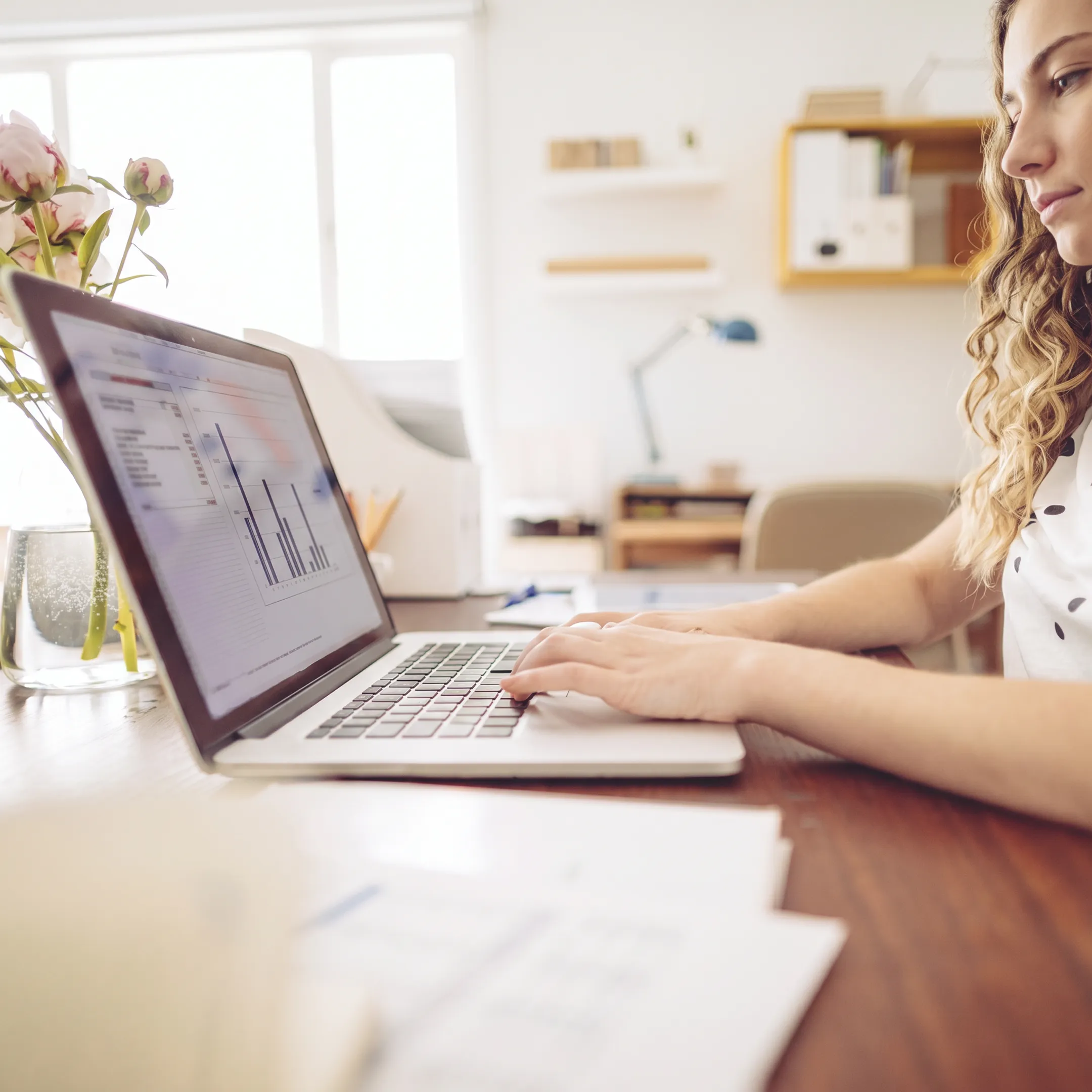Professional comparing financial records on a laptop