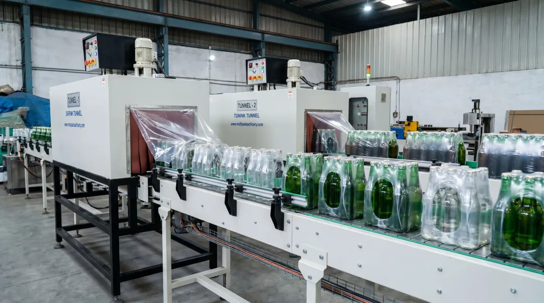 Glass bottle multipack shrink wrapping line with vertical bottle orientation on conveyor