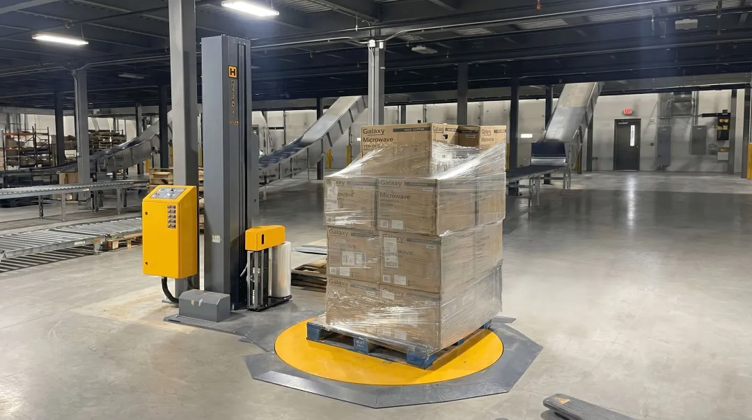 Semi-automatic turntable stretch wrapper machine on warehouse floor