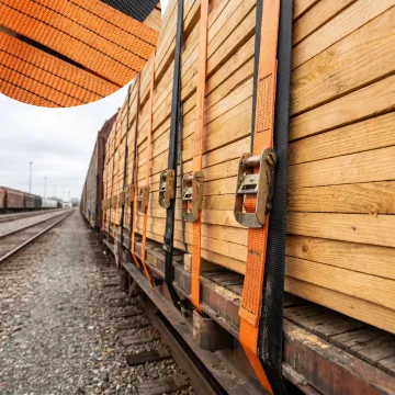 Polyester strapping securing bundled lumber on a rail load