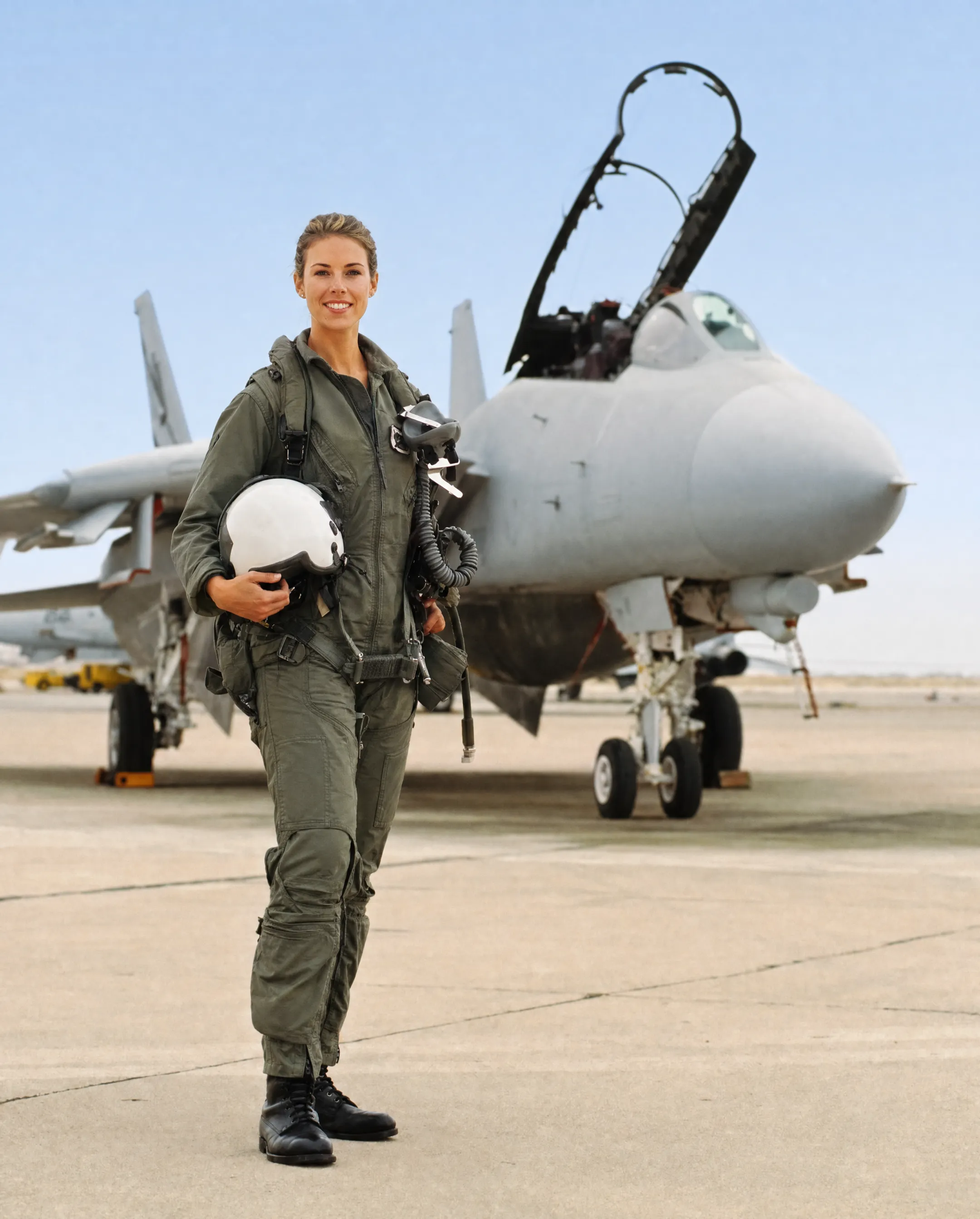 Female fighter pilot in flight suit standing beside military jet