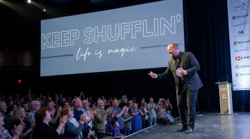 Jon Dorenbos performing sleight-of-hand magic during a corporate keynote presentation
