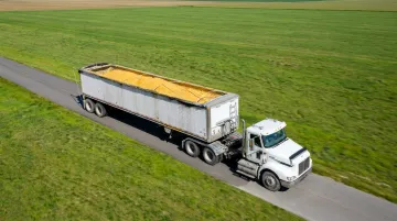 Semi-truck hauling grain on rural highway during harvest season