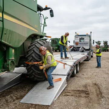 Heavy-haul team securing a combine for transport