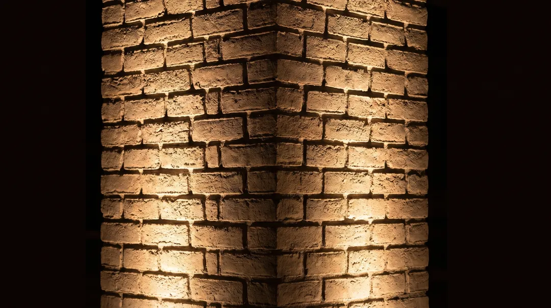 Historic brick column with grazing uplight emphasizing texture mortar joints and architectural detail
