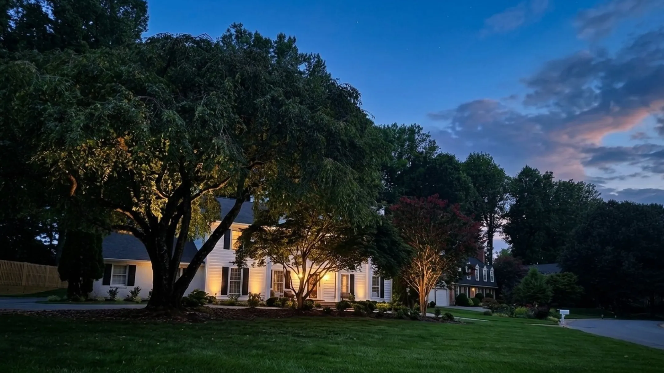 Residential exterior combining soffit downlighting with landscape uplighting on house facade at night