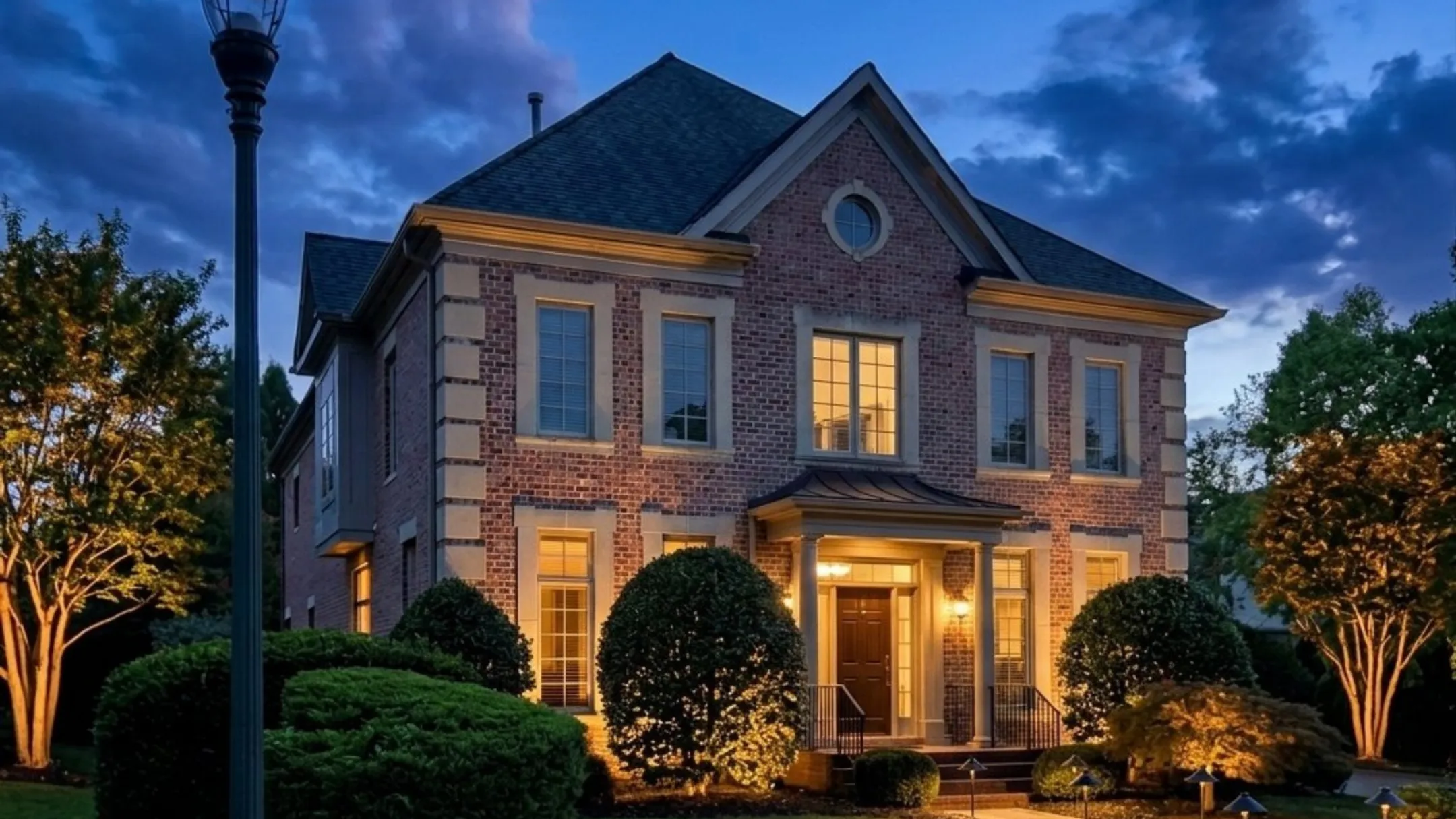 Historic Federal-style home with professionally designed low voltage landscape lighting at dusk