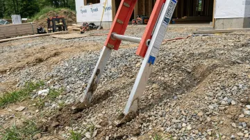 Level-EZE automatic ladder leveler attached to extension ladder on uneven terrain