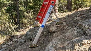 Level-EZE automatic ladder leveler attached to ladder base on uneven slope