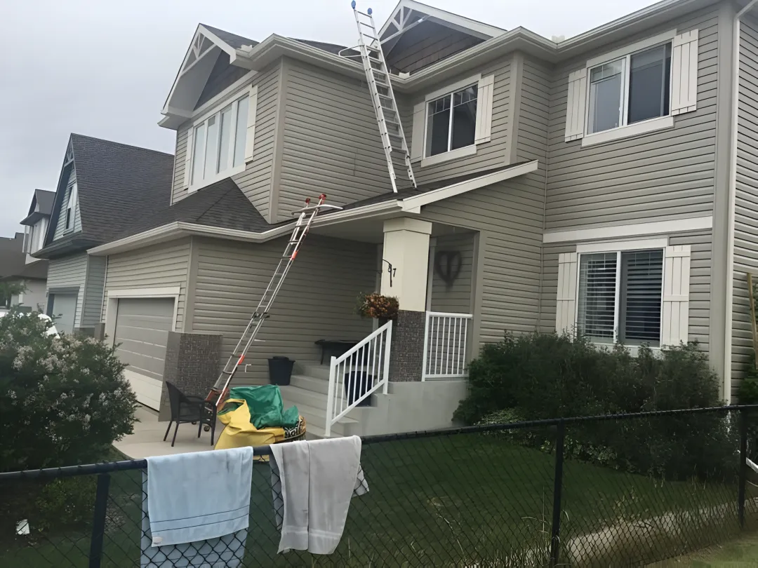 Worker safely using a ladder on an uneven surface with Level-EZE automatic levelers installed