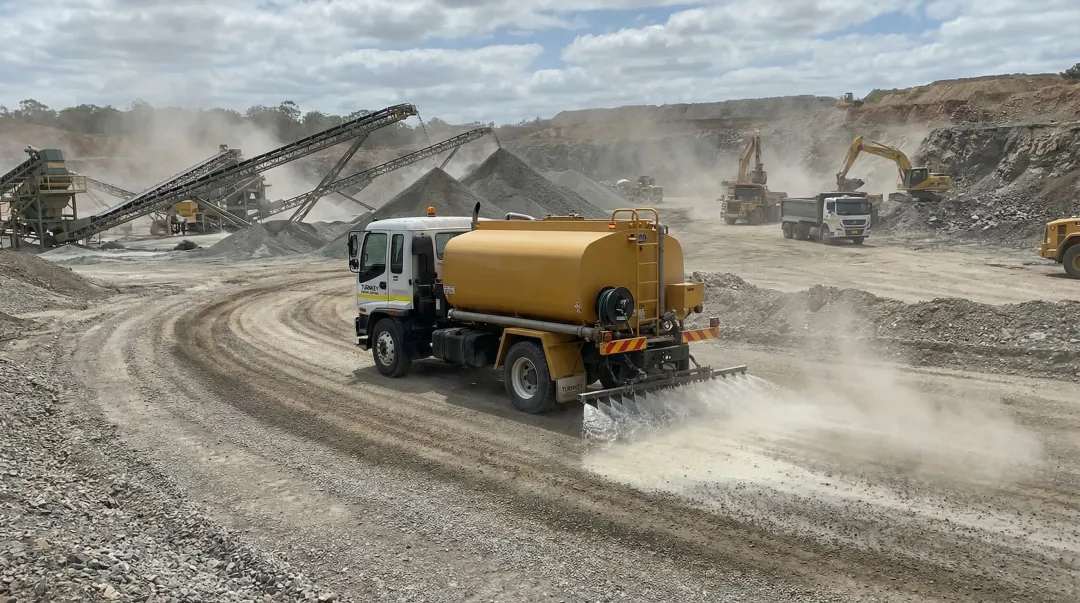 Water truck applying chemical dust suppressant to quarry haul road surface
