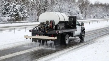 Aerial view of highway salt brine spray truck treating roads before winter storm