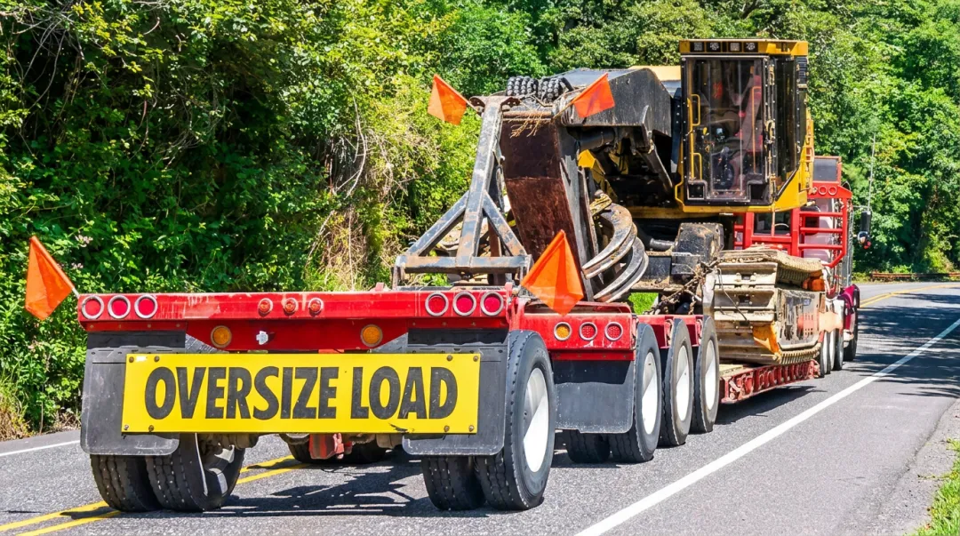 Specialized flatbed heavy-haul truck transporting oversized industrial equipment on highway