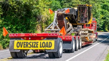 Specialized flatbed heavy-haul truck transporting oversized industrial equipment on highway