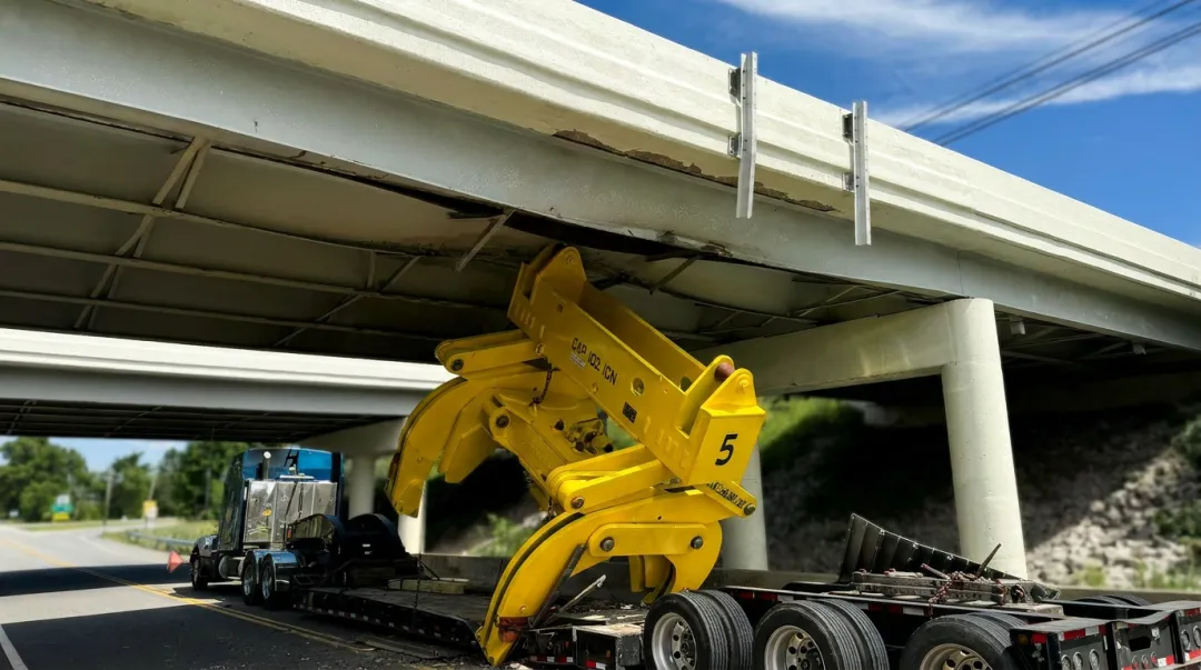 Oversize load truck striking low bridge causing infrastructure damage on highway