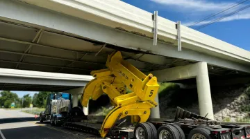 Oversize load truck striking low bridge causing infrastructure damage on highway