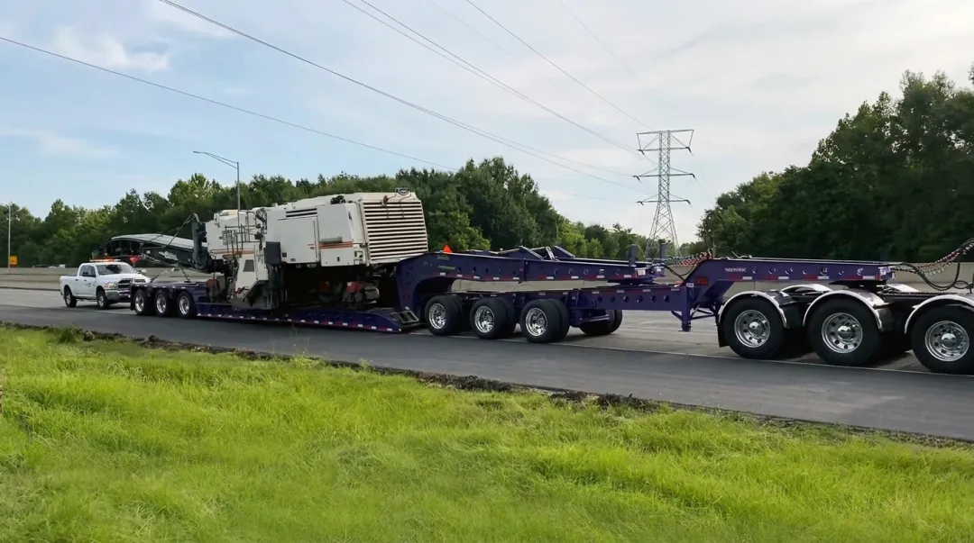 Heavy haul multi-axle lowboy trailer transporting large industrial machinery on highway
