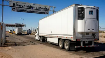 Refrigerated truck crossing US Mexico border at commercial customs checkpoint