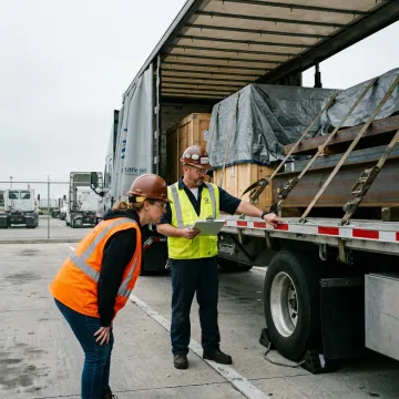 Logistics team coordinating Conestoga flatbed shipment
