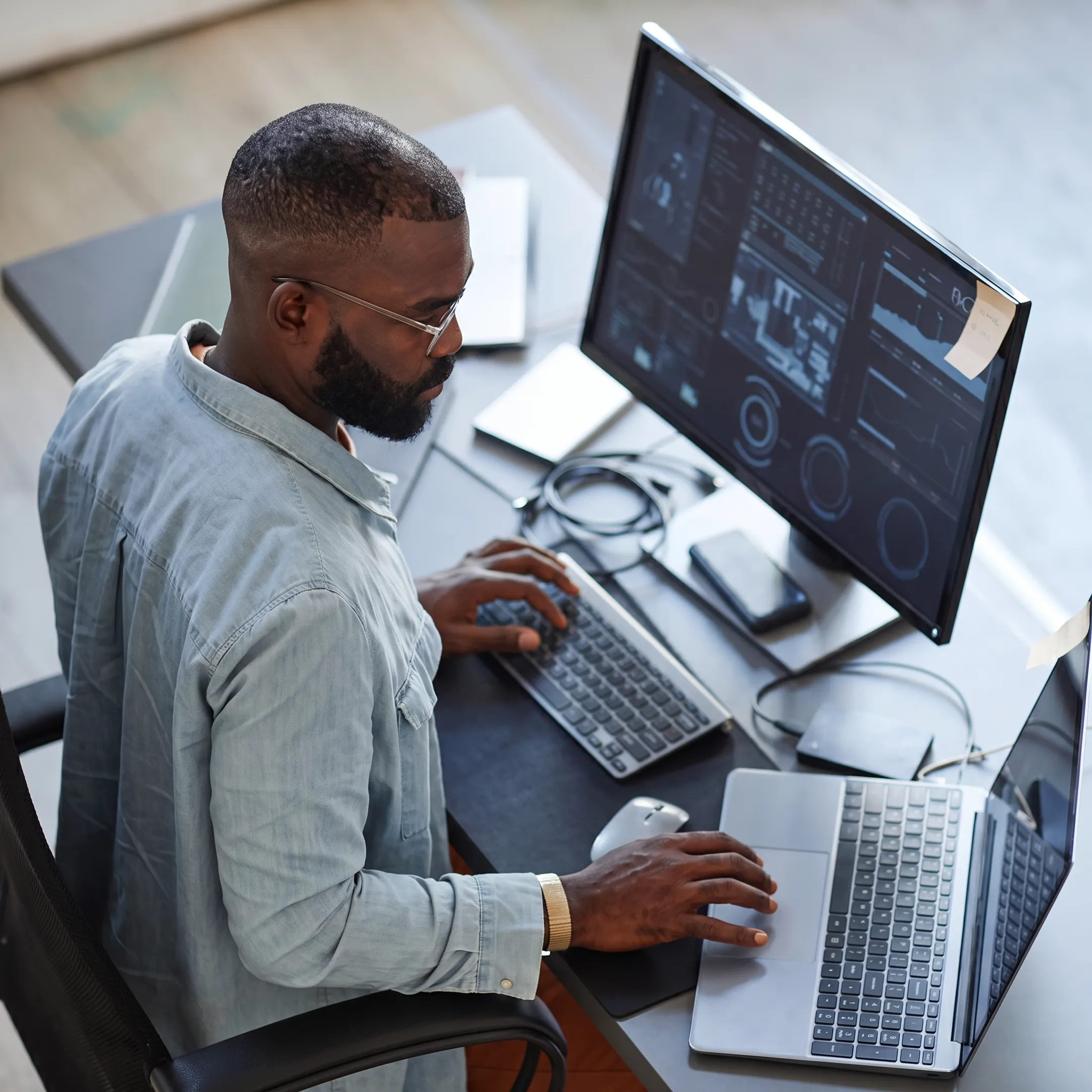 Security professional monitoring business systems on multiple screens