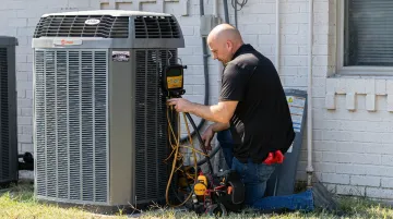 HVAC technician testing repaired air conditioner condenser unit outdoors