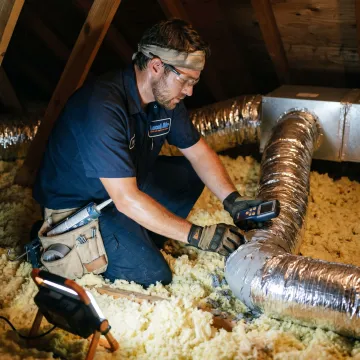 Technician repairing air conditioning ducts