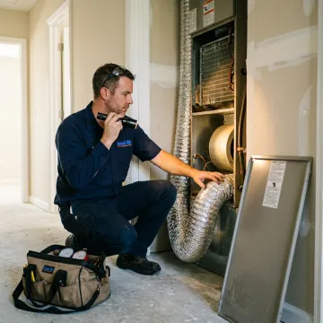Technician inspecting HVAC equipment during a home service visit