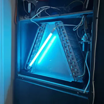 Close-up of UV-C light glowing inside air conditioning evaporator coil