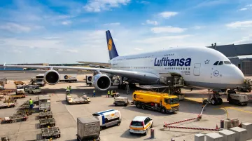 Commercial aircraft on airport ramp surrounded by ground support equipment fleet