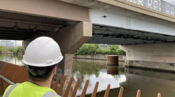 UAV drone conducting infrastructure bridge inspection over water using real-time telemetry
