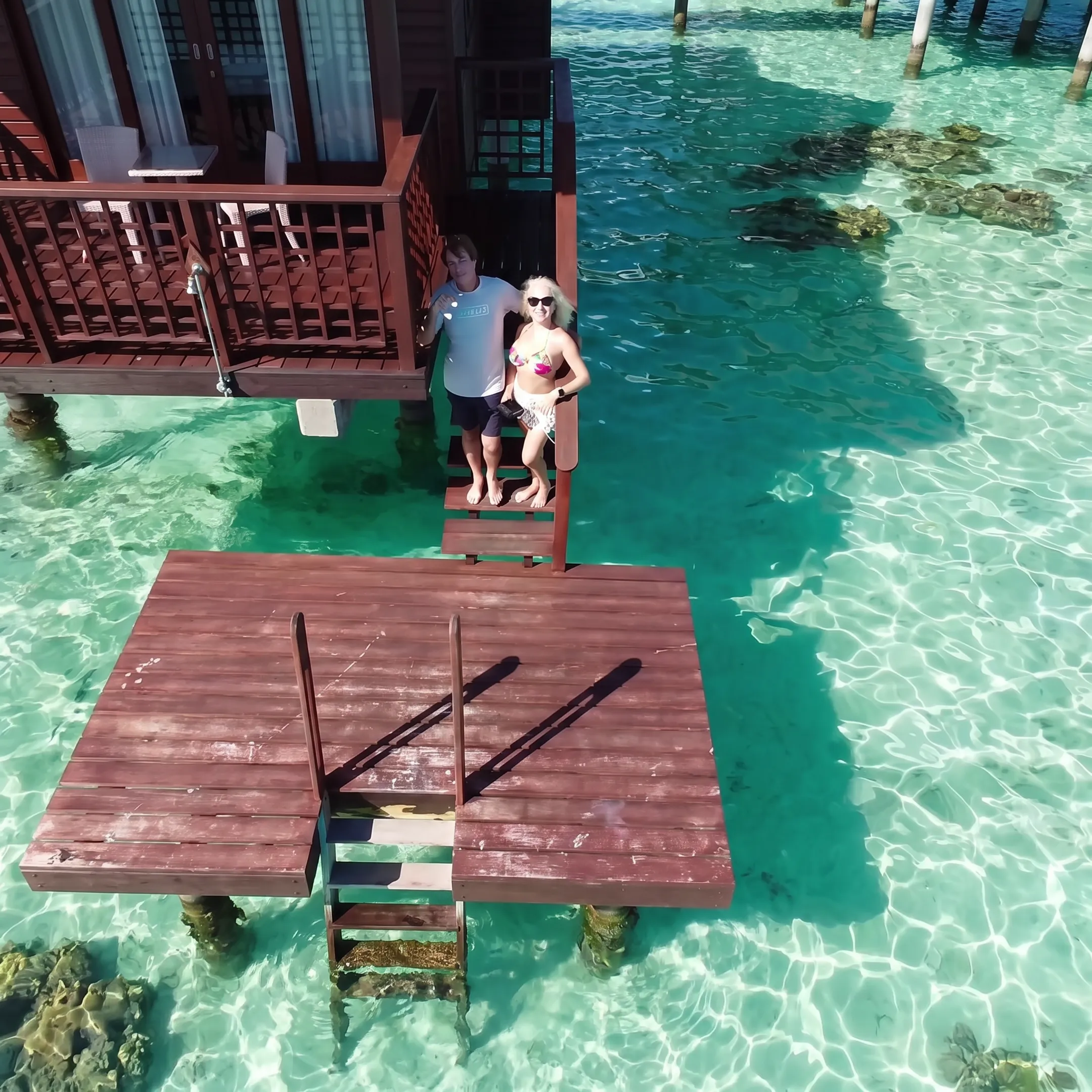 Couple celebrating a Bora Bora wedding beside an overwater bungalow