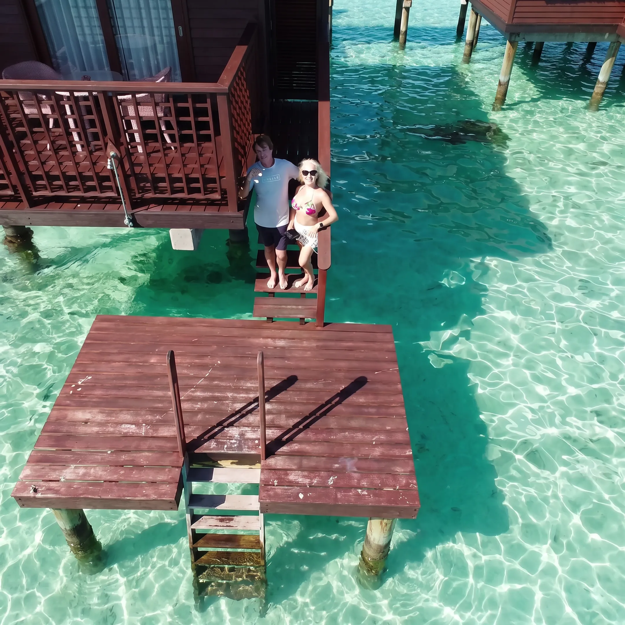 Family relaxing on an overwater bungalow deck above a tropical lagoon