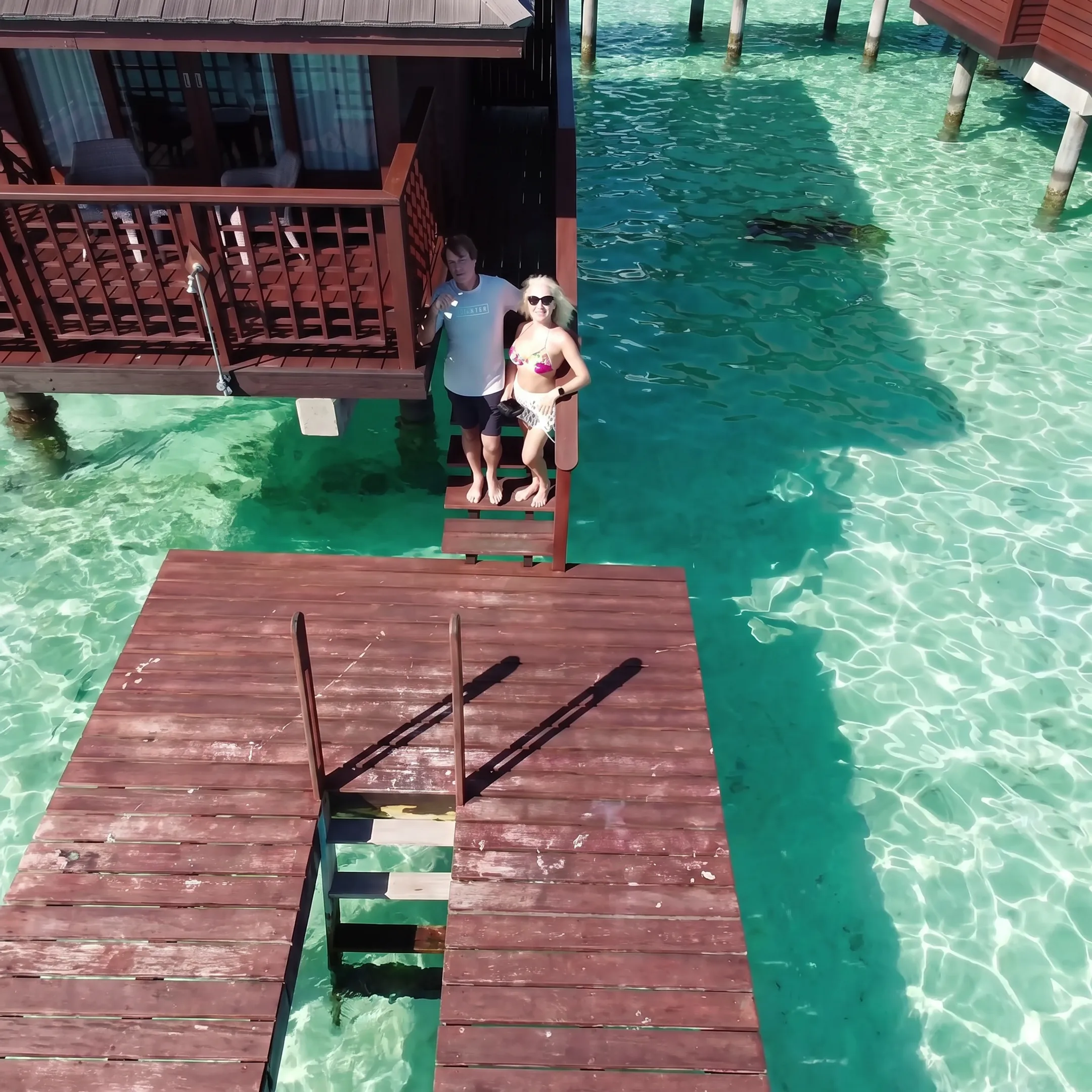 Couple relaxing beside an overwater bungalow in Moorea