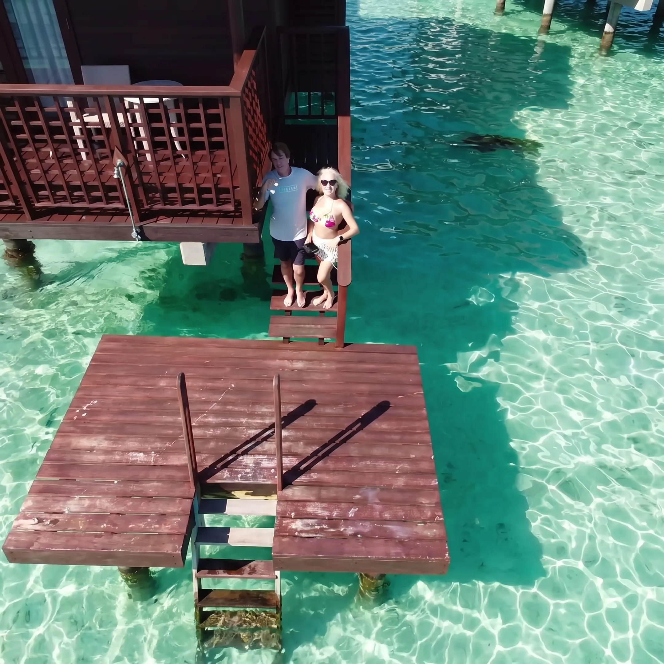 Couple relaxing on a Tahiti overwater bungalow deck