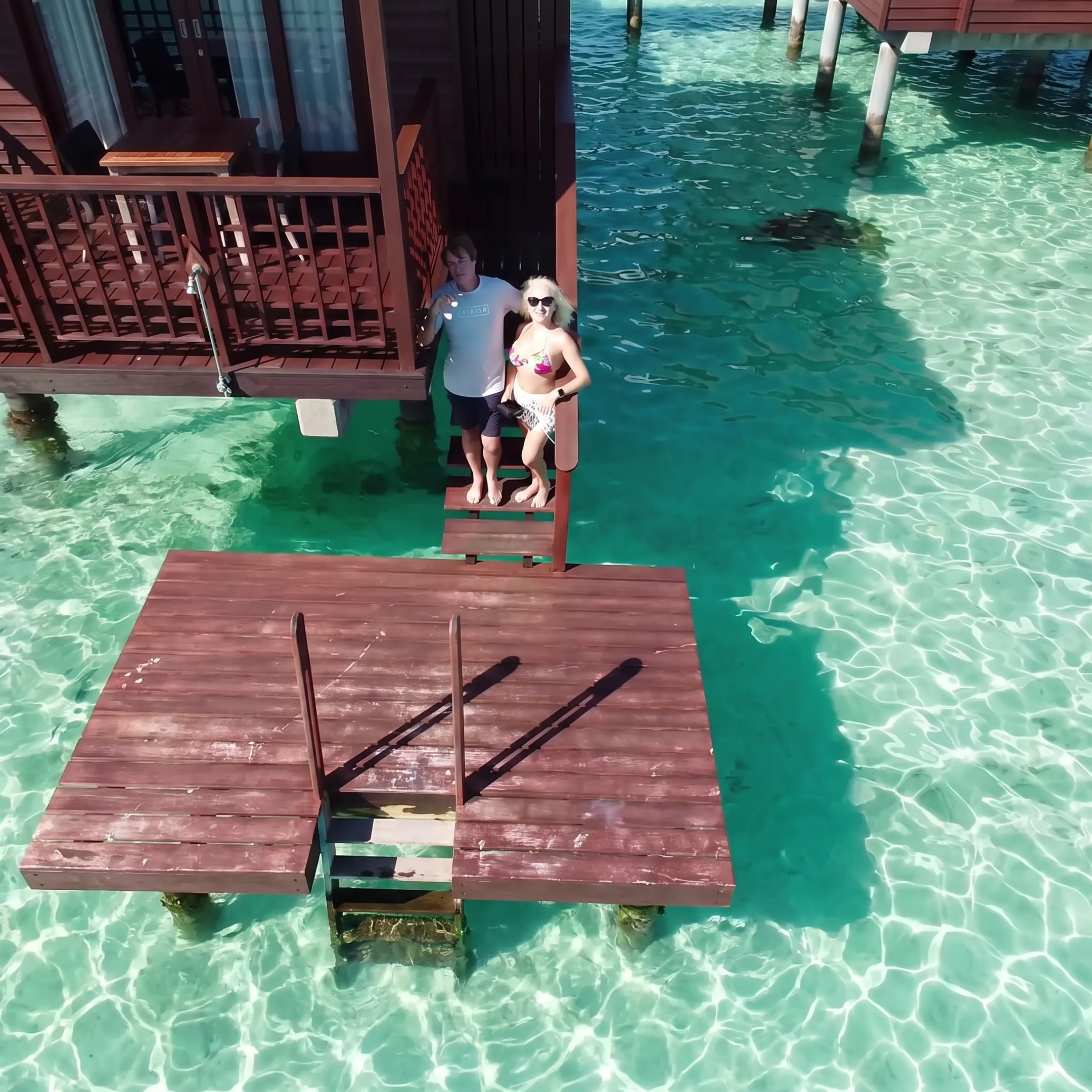 Couple relaxing in a Tahiti overwater bungalow overlooking a turquoise lagoon