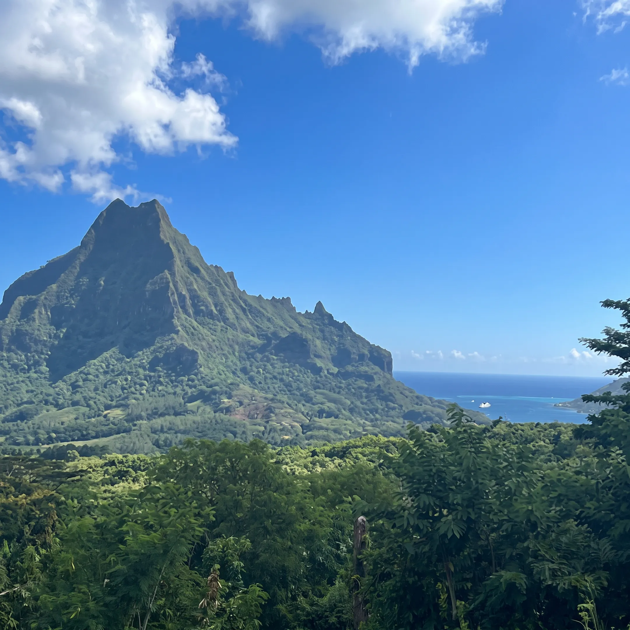 Small expedition cruise ship sailing past rugged Marquesas Islands scenery in French Polynesia
